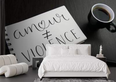 AMOUR ≠ VIOLENCE lettrage dans cahier avec tasse d'espresso et stylos sur bureau noir Wall mural