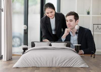 A woman and a man are sitting at a desk with a laptop in front of them Wall mural