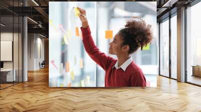 African American female employee write down on colorful sticky notes manage list, concentrated biracial woman work on startup brainstorm collaborate plan on stickers on glass wall Wall mural