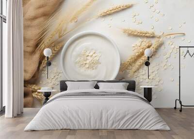 Oat milk in a glass and mug on a background. Flakes and ears for oatmeal and granola on a wooden plate. Wall mural