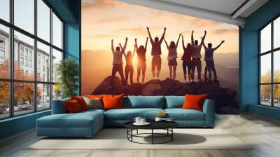 Joyful group of people cheering and being happy on mountain top at sunset Wall mural