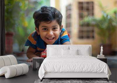 Little happy Indian boy plays with toy car Wall mural