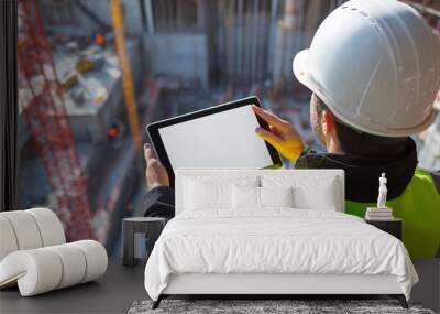 An architect wearing a hard hat at a construction site checks the details of his work while looking at a tablet. Generative AI Wall mural