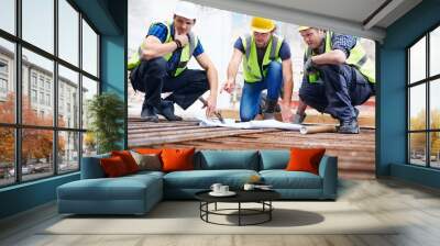 Construction workers engineer reviewing blueprints at construction site Wall mural