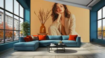 A woman is sitting on a stool with a vase of flowers in front of her Wall mural