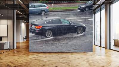 Car driving fast on wet road, driving through puddle during heavy rain. Car driving on flooded asphalt road. Dangerous driving conditions, wet road risk of aquaplaning. Slippery road, low visibility Wall mural