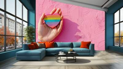 holding a rainbow heart on a pink background Wall mural