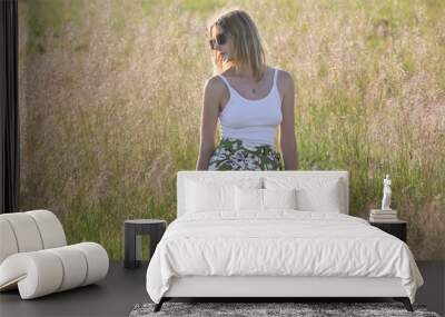 Candid outdoor portrait on the meadow of young woman linen skirt and white top. Casual summer fashion.  Wall mural