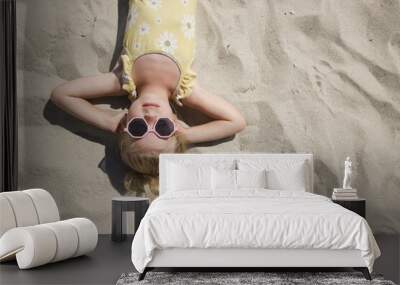 Happy little girl laying on the sand, top view Wall mural