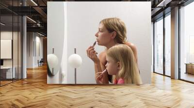 Mother and daughter applying lipstick in front of mirror Wall mural