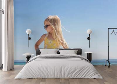 Portrait of 4 years old girl in yellow swimsuit and long blonde hair with blue sea and sky on the sandy beach	 Wall mural