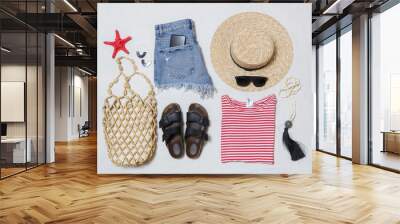 Simple summer outfit, denim shorts and striped cotton shirt with accessories on white background. Women's casual fashion items, top view. Wall mural