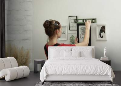 Woman arranging picture frames on wall in new house, diy home improvement concept Wall mural