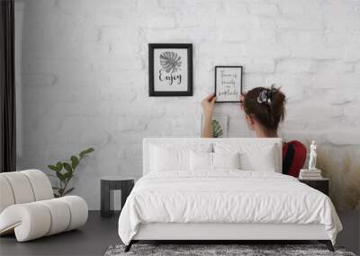 Woman arranging picture frames on wall in new house, diy home improvement concept Wall mural