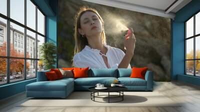 Woman spraying facial mist on her face, summertime skincare concept Wall mural