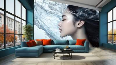 Woman with long black hair standing in front of a water splash, eyes closed. Wall mural