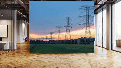 Group silhouette transmission towers (steel lattice/power tower, electricity pylon) next to apartment complex at sunset in US. Texture high voltage pillar, overhead power line, industrial background. Wall mural