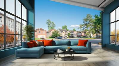 Suburban residential area, row of modern townhomes in Humble, Texas, US. Red brick houses surrounded with tall pine trees, cloud blue sky. Panorama view street intersection and multi-story townhouses. Wall mural