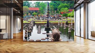 Ancient water palace Tirta Gangga with fountains, natural pools, path in fish pond with statues of dancing women in traditional costumes. Culture, arts of Bali, popular travel destination in Indonesia Wall mural