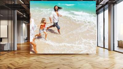 Happy family - young father, mother, baby girl hold hands, run together, child jump with fun by water pool along sea surf on tropical beach. Travel lifestyle, people walk with kid on summer vacation. Wall mural