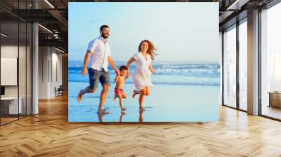 Happy family - young father, mother, baby son run together, child jump with fun by water pool along sunset sea surf on tropical beach. Travel lifestyle, people walking with kid on summer vacation Wall mural