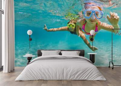 Young mother with child in snorkeling mask dive in coral reef sea lagoon to explore underwater world. Family travel lifestyle in summer adventure camp. Swimming activities on beach vacation with kids. Wall mural