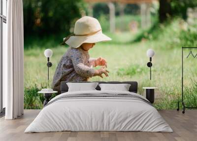 baby girl seating on the grass - summer day of childhood, straw hat, copy space Wall mural