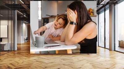 Mother working from home with baby toddler. Crying child and stressed woman. Stay home Wall mural