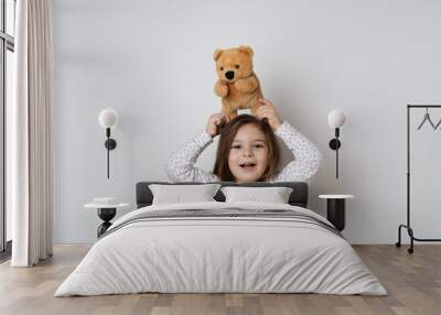 Young pretty caucasian girl with vintage teddy bear in pyjamas in white studio  Wall mural