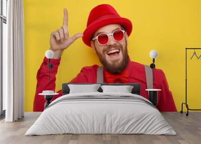 A man in a red hat and glasses is smiling and pointing to the sky. Concept of fun and playfulness, as the man is enjoying himself and possibly pointing out something interesting or amusing Wall mural