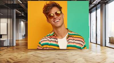 A man wearing a striped shirt and sunglasses is smiling. The image has a bright and cheerful mood, with the man's smile and the colorful outfit Wall mural