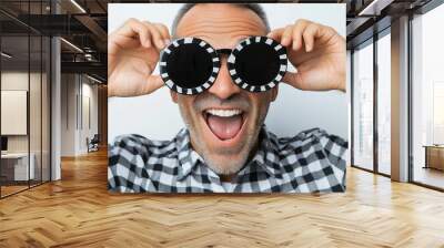 A man wearing sunglasses and a plaid shirt is smiling and laughing. He is wearing a pair of black and white sunglasses Wall mural