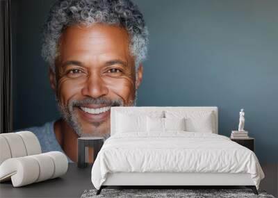 A man with a gray beard and a gray shirt is smiling. He has a very friendly and approachable look Wall mural