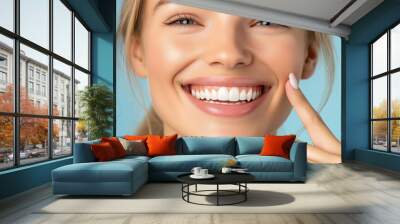 A woman with a smile on her face is pointing to her teeth. Concept of confidence and positivity, as the woman is proud of her smile and is showing it off Wall mural