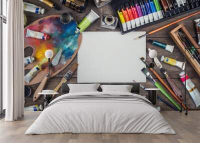 Set of artist accessories. Canvas, tube of oil paint, art brushes, palette knife lying on the wood table. Artist workshop background. Wall mural