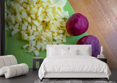 Ingredients for borshch on a green cutting board - potatoes and two beets, wooden background Wall mural