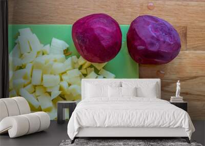 Ingredients for borshch on a green cutting board - potatoes and two beets, wooden background Wall mural