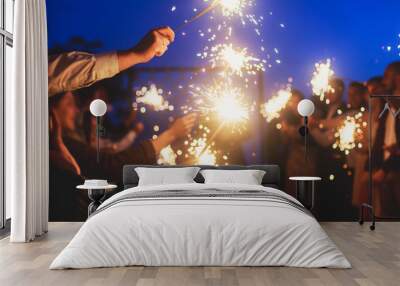 A crowd of young happy people with sparklers in their hands during birthday celebration Wall mural