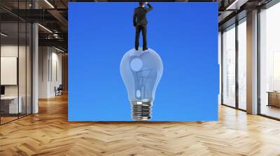 Businessman standing on light bulb Wall mural