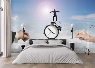 Two hands pulling rope businessman balancing on alarm clock Wall mural