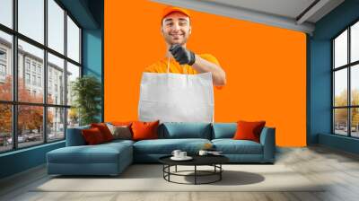 Delivery man with paper bag, clipboard. Courier in uniform cap and t-shirt  service fast delivering orders. Young guy holding a cardboard package. Character for advertising Wall mural