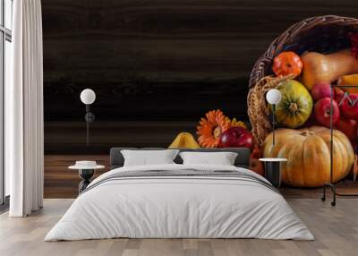 Thanksgiving day background with empty copy space. Pumpkin harvest in wicker basket. Squash, orange vegetable autumn fruit, apples, and nuts on a wooden table. Halloween decoration fall design Wall mural