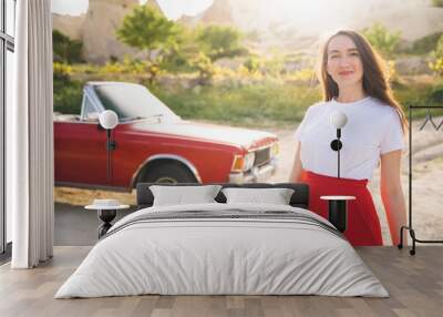 beautiful happy girl in a skirt posing near a retro car in the mountains of cappadocia Wall mural