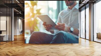 Close up of young businessman using digital tablet while sitting at his working place in office. Businessman using digital tablet Wall mural