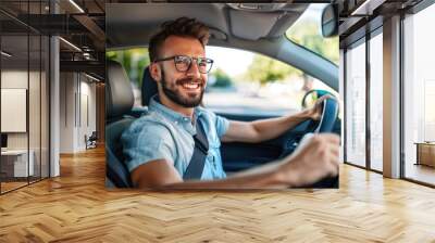 Handsome young man is driving a car and smiling driving a car with a clear view of the city through the window. showcasing safe driving with a seatbelt Wall mural