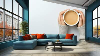 Woman's hands holding a cup of coffee on a light background, top view. Flat lay with copy space for design Wall mural