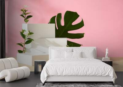 Abstract minimal scene - stack of white empty podiums with green leaf and flower branches decorated on pink background and natural leaf shadows. Space for display product. Front view Wall mural