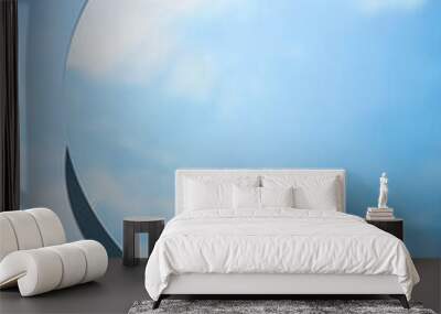 Abstract minimal scene with round mirror placed on blue background. The mirror reflects the clear blue sky and white clouds. Copy space Wall mural