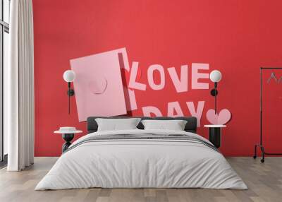 The words LOVE DAY and two pastel pink cards stand out on the red background. Ideal advertising space for Valentine's Day. Flat lay, top view. Wall mural