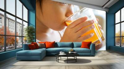 Asian little happy girl drinking orange juice for her breakfast Wall mural